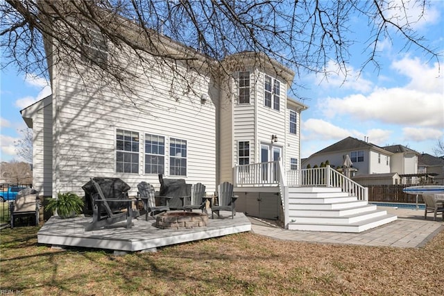 rear view of property with fence, an outdoor fire pit, a yard, a deck, and a patio area