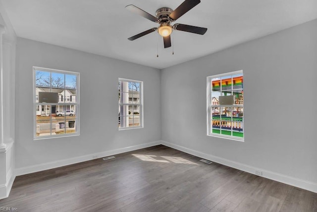 spare room with a wealth of natural light, baseboards, and wood finished floors