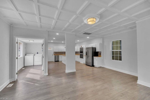 unfurnished living room featuring washer and dryer, visible vents, baseboards, and light wood finished floors