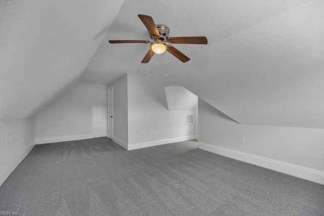 additional living space with baseboards, lofted ceiling, a textured ceiling, and dark carpet