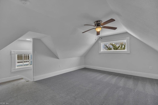 bonus room with baseboards, a ceiling fan, lofted ceiling, and dark carpet