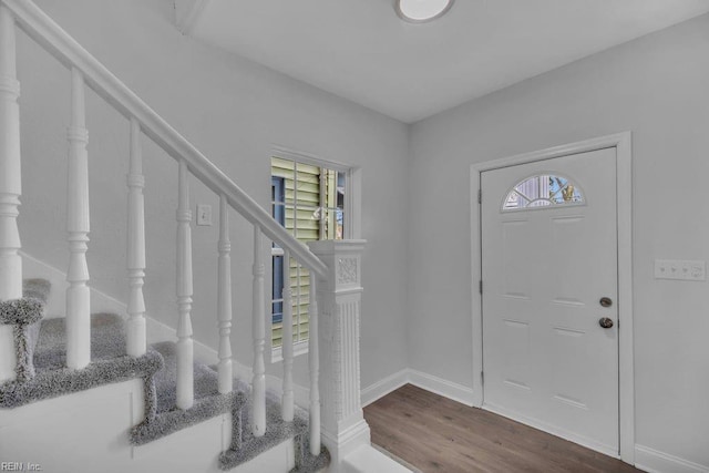 foyer entrance with stairway, baseboards, a healthy amount of sunlight, and wood finished floors