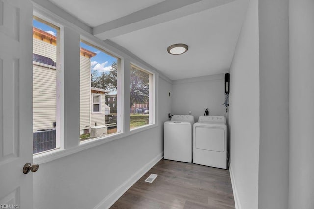 laundry area featuring washing machine and clothes dryer, visible vents, baseboards, laundry area, and wood finished floors