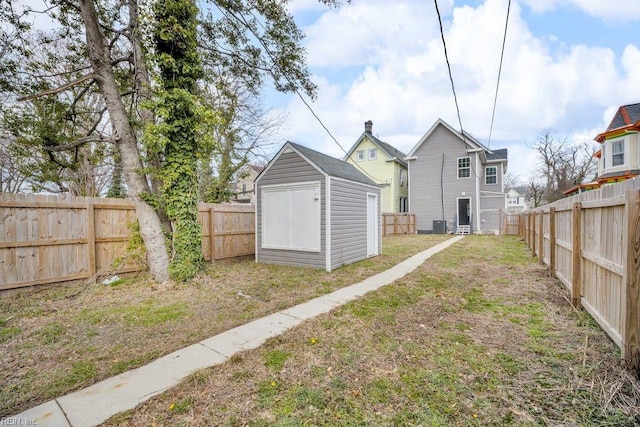 view of yard with central air condition unit, an outbuilding, a fenced backyard, and a shed