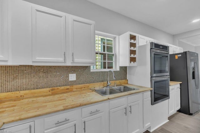 kitchen with white cabinets, tasteful backsplash, appliances with stainless steel finishes, and a sink