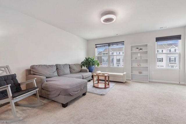 living area featuring a wealth of natural light, baseboards, carpet floors, and visible vents