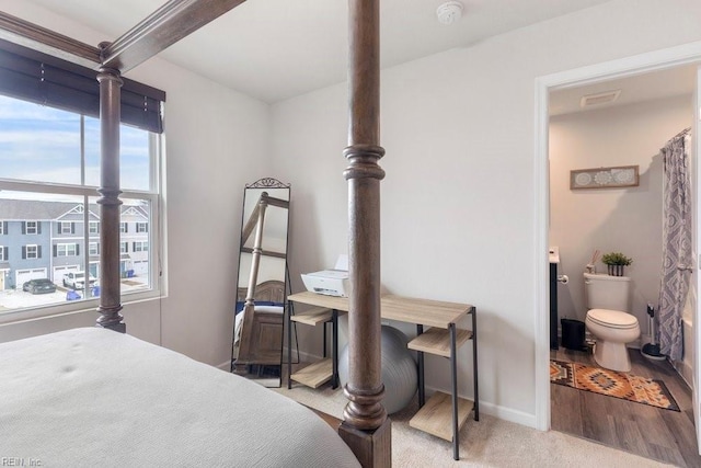 bedroom featuring beamed ceiling, baseboards, and wood finished floors