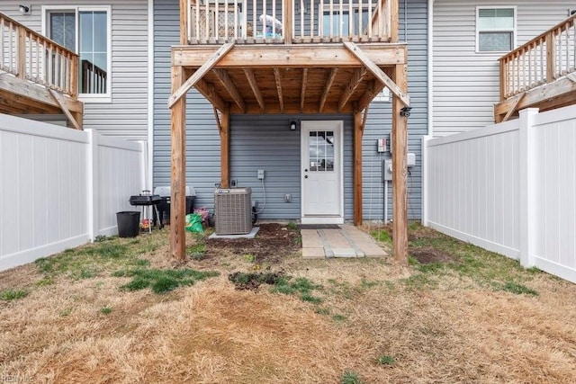 doorway to property with central AC unit and fence