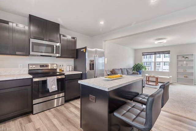 kitchen with a kitchen bar, light countertops, open floor plan, and appliances with stainless steel finishes