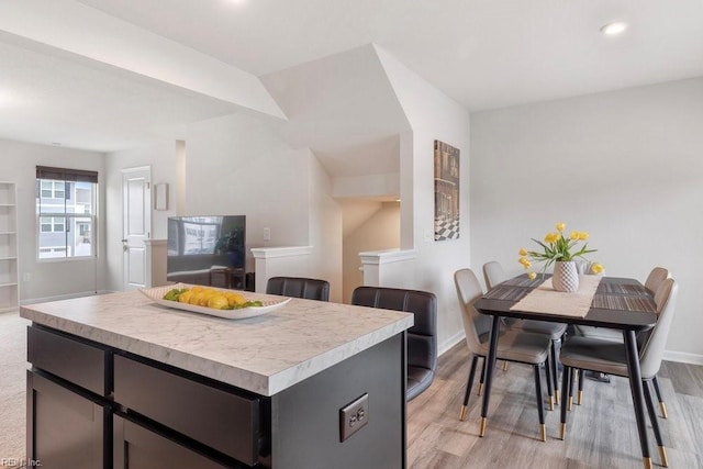 kitchen with baseboards, a kitchen island, recessed lighting, light countertops, and light wood-style floors