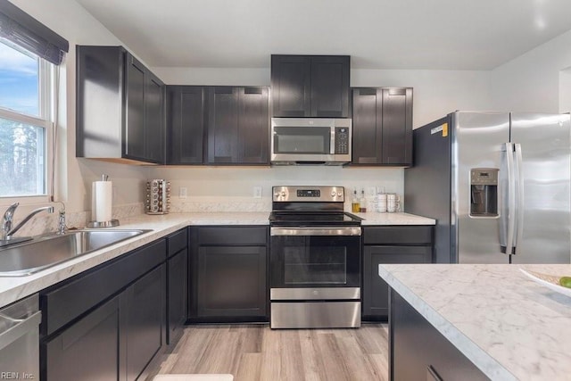 kitchen featuring light countertops, light wood finished floors, appliances with stainless steel finishes, and a sink