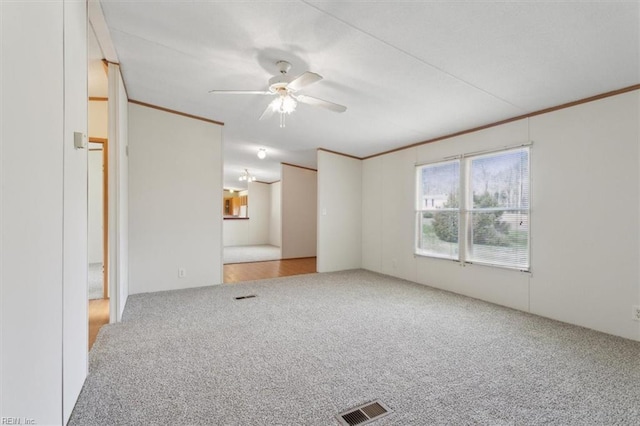 interior space with a ceiling fan, crown molding, carpet, and visible vents