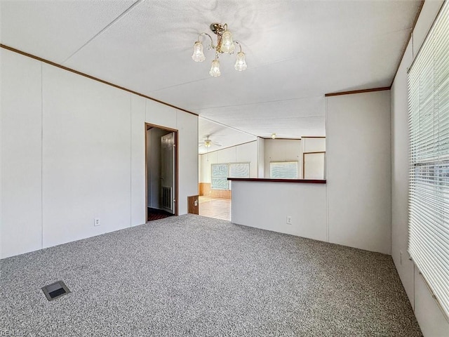 unfurnished room featuring visible vents, ceiling fan with notable chandelier, crown molding, and carpet