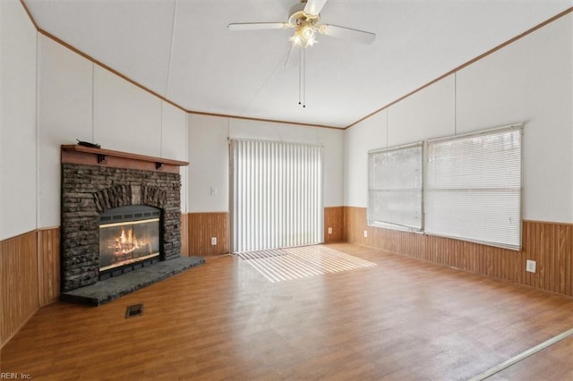 unfurnished living room with a glass covered fireplace, wood finished floors, a wainscoted wall, and wood walls