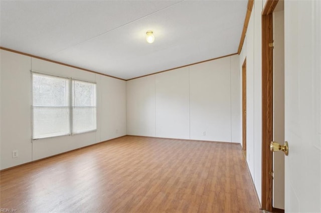 spare room featuring crown molding and light wood-type flooring