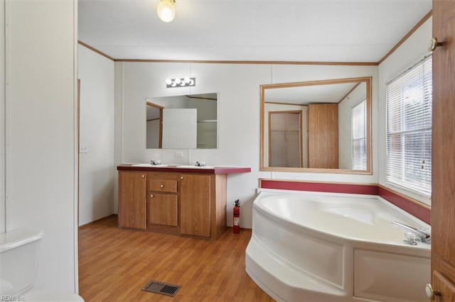 bathroom featuring visible vents, a garden tub, a healthy amount of sunlight, and wood finished floors