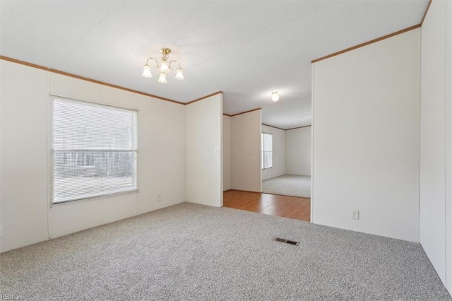 unfurnished room with an inviting chandelier, crown molding, carpet, and visible vents