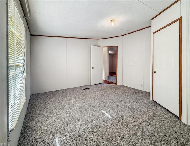 unfurnished bedroom featuring carpet flooring, visible vents, and ornamental molding