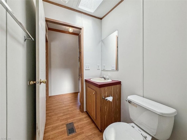 bathroom with vanity, wood finished floors, visible vents, crown molding, and toilet