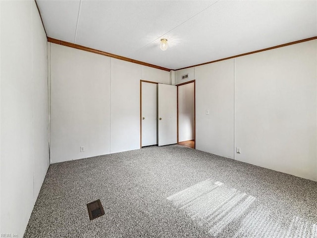 carpeted empty room with visible vents and crown molding