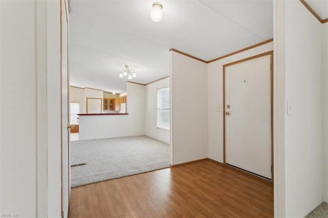 carpeted entrance foyer featuring crown molding and wood finished floors