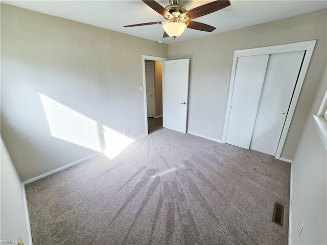 unfurnished bedroom featuring a closet, carpet floors, baseboards, and visible vents