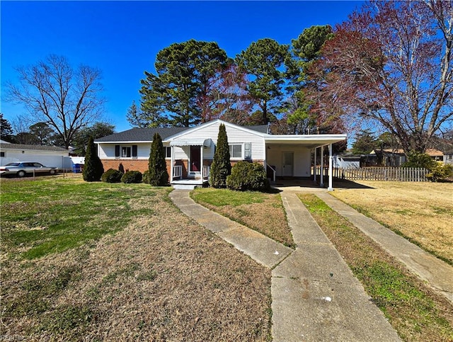 view of front facade featuring an attached carport, brick siding, a front lawn, and fence