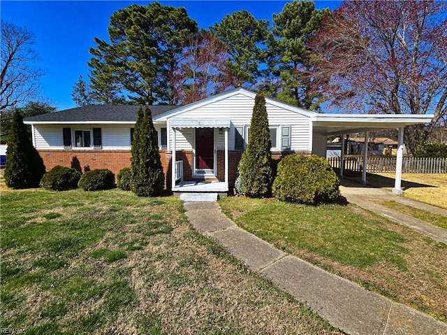 view of front facade with a carport, brick siding, a front lawn, and fence