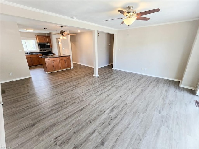 unfurnished living room with visible vents, wood finished floors, crown molding, baseboards, and ceiling fan