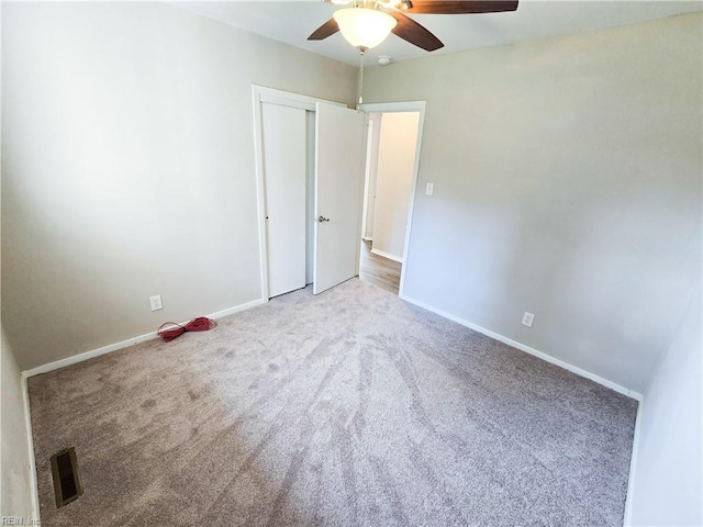 unfurnished room featuring visible vents, baseboards, carpet, and ceiling fan