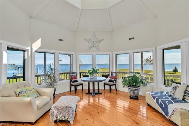 sunroom / solarium with visible vents, lofted ceiling, and a water view