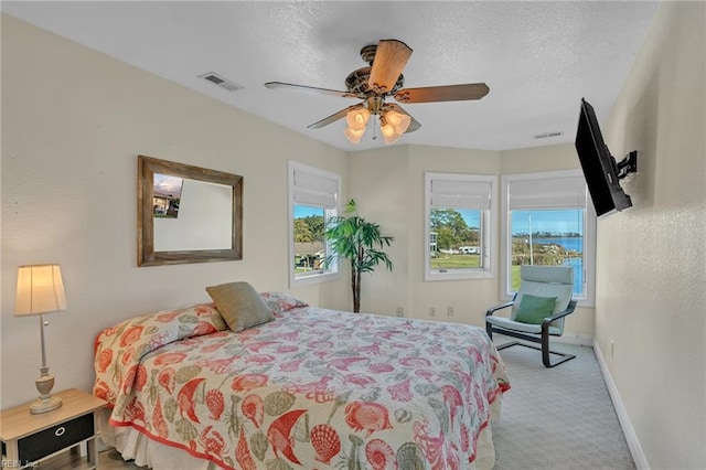 bedroom featuring baseboards, visible vents, ceiling fan, a textured ceiling, and carpet flooring