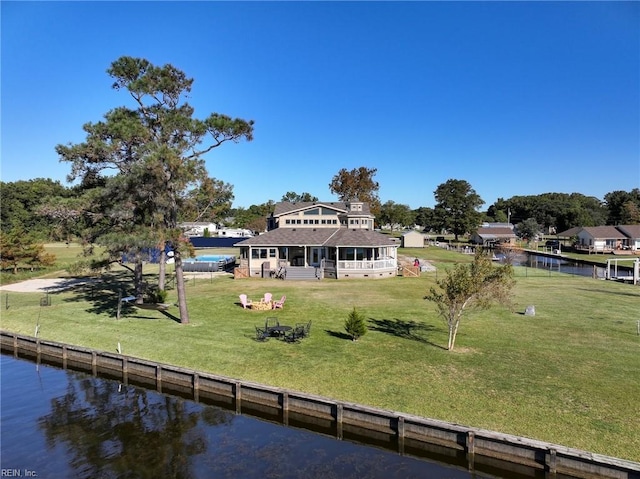 back of house featuring a lawn, a water view, and a sunroom