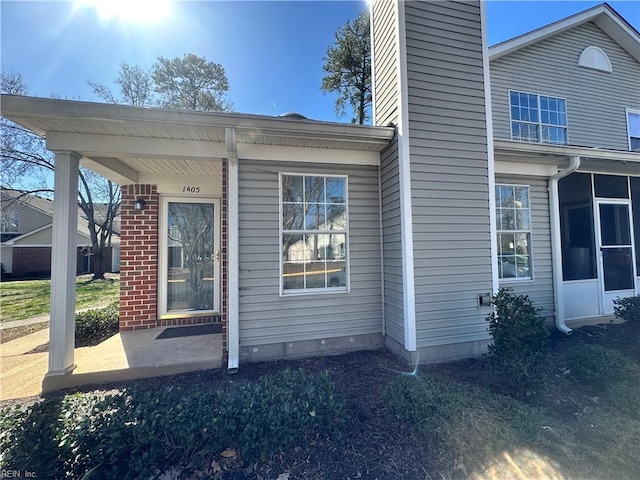 view of property exterior with brick siding and a sunroom