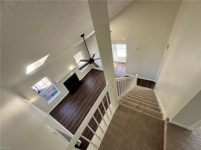 stairs featuring high vaulted ceiling, a textured ceiling, carpet flooring, baseboards, and ceiling fan