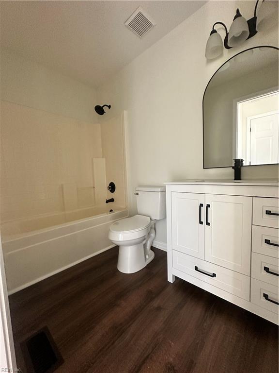 bathroom with vanity, toilet, wood finished floors, and visible vents