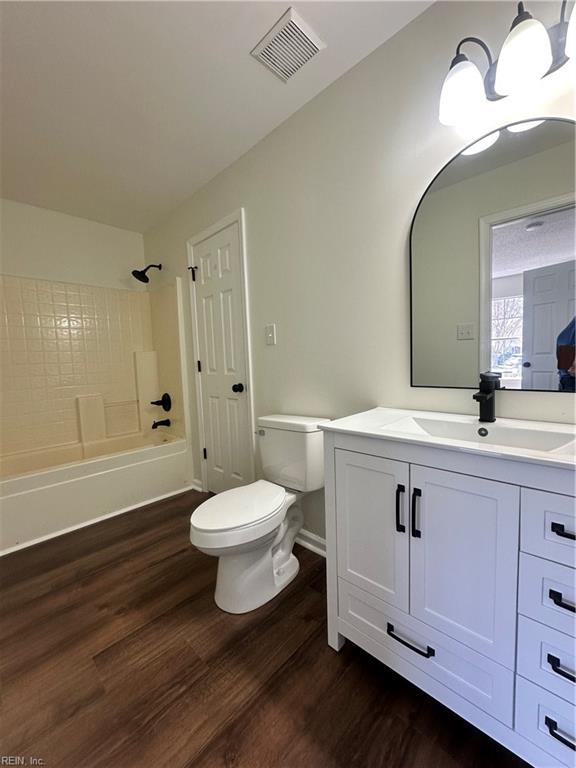 full bath with vanity, wood finished floors, visible vents,  shower combination, and toilet