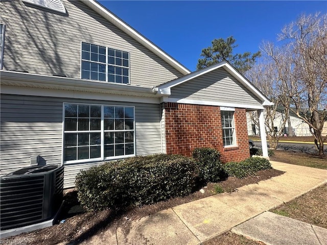 view of side of home with brick siding and central AC unit