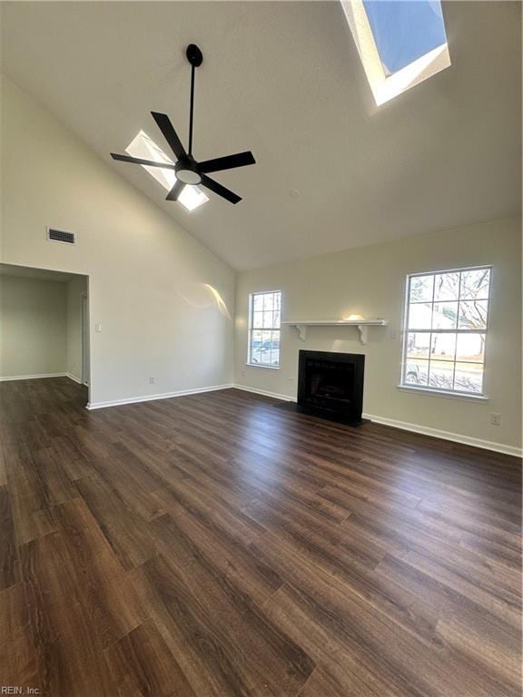 unfurnished living room with visible vents, a skylight, a fireplace with flush hearth, and a ceiling fan