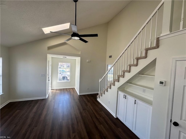 entrance foyer with a ceiling fan, stairs, a skylight, baseboards, and dark wood-style flooring