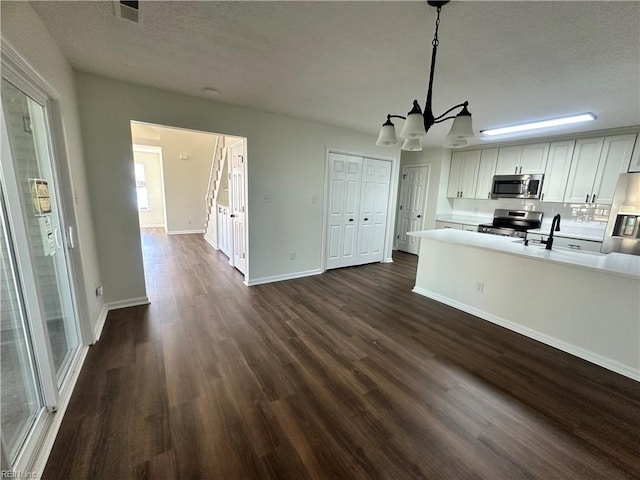 kitchen featuring a sink, appliances with stainless steel finishes, dark wood-style flooring, and light countertops