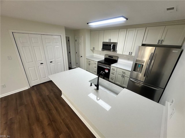 kitchen with visible vents, a sink, dark wood finished floors, stainless steel appliances, and light countertops