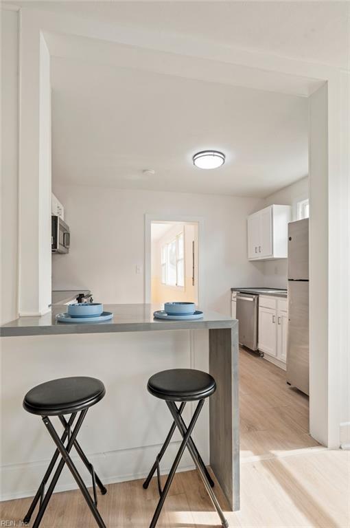 kitchen featuring white cabinetry, a kitchen breakfast bar, stainless steel appliances, and a peninsula