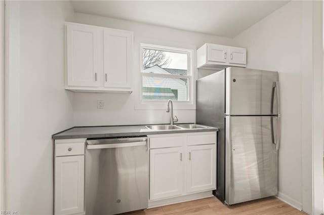 kitchen featuring light wood finished floors, white cabinetry, stainless steel appliances, and a sink