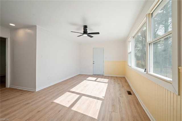 unfurnished room with light wood-style flooring, a ceiling fan, and baseboards