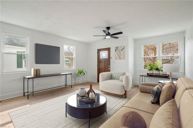 living area featuring wood finished floors, baseboards, and ceiling fan