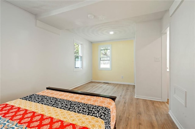 bedroom with light wood finished floors and baseboards