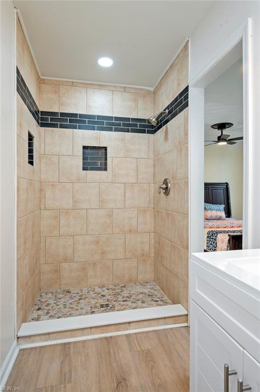 ensuite bathroom featuring connected bathroom, tiled shower, vanity, and a ceiling fan