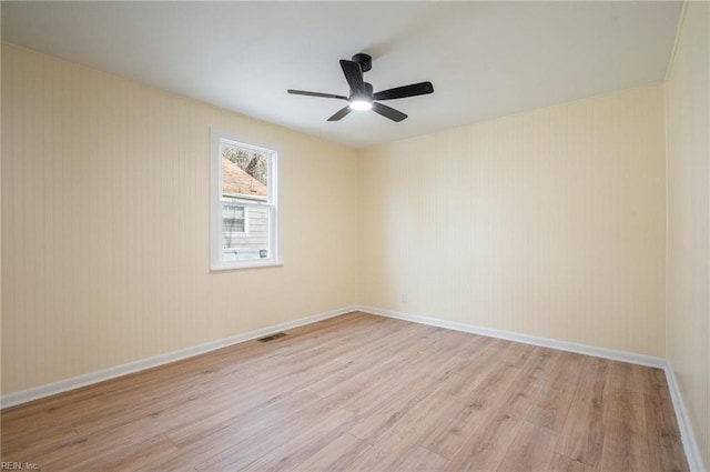 empty room with a ceiling fan, visible vents, baseboards, and light wood finished floors