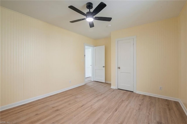 empty room featuring a ceiling fan, light wood-type flooring, and baseboards